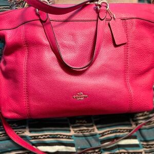 Magenta (pink) Coach handbag. Medium size. Has handles and strap.